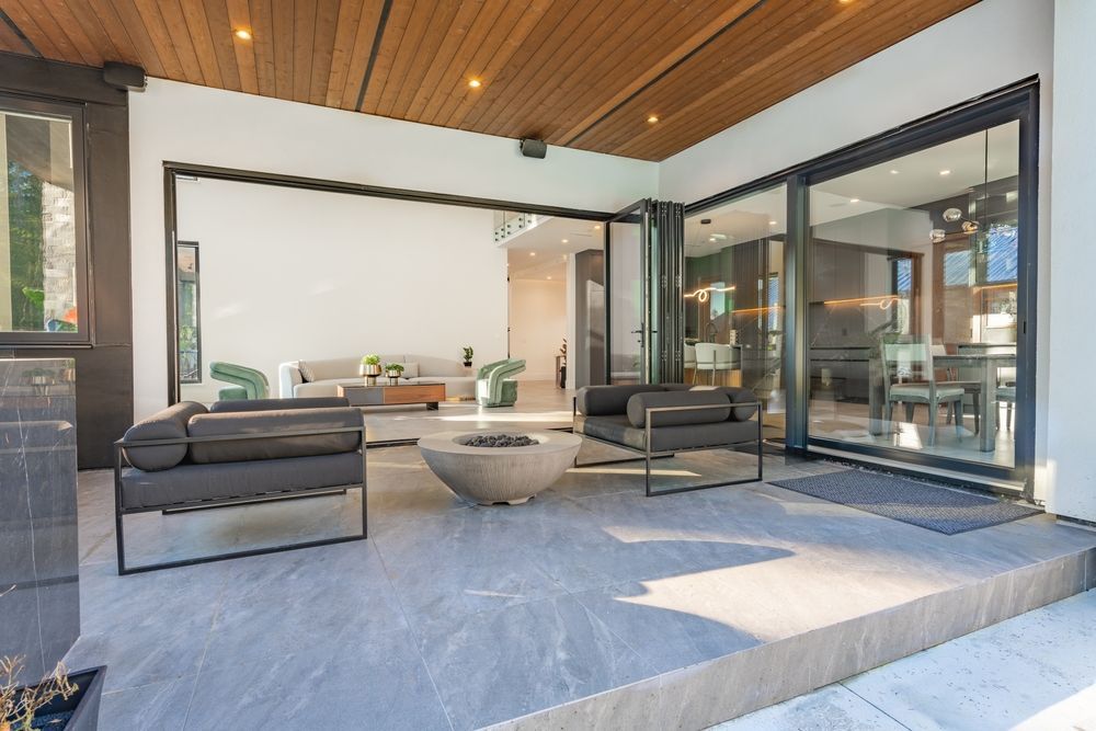 Patio with modern gray furniture, fire pit, and sliding glass doors leading indoors.