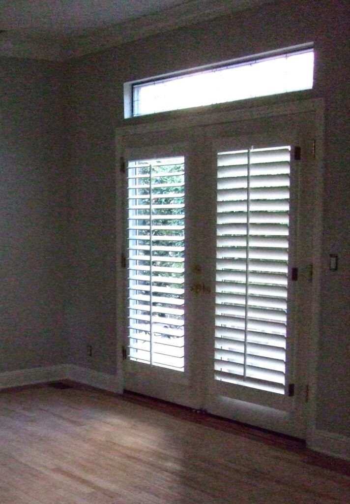 An empty room with shuttered doors and a window