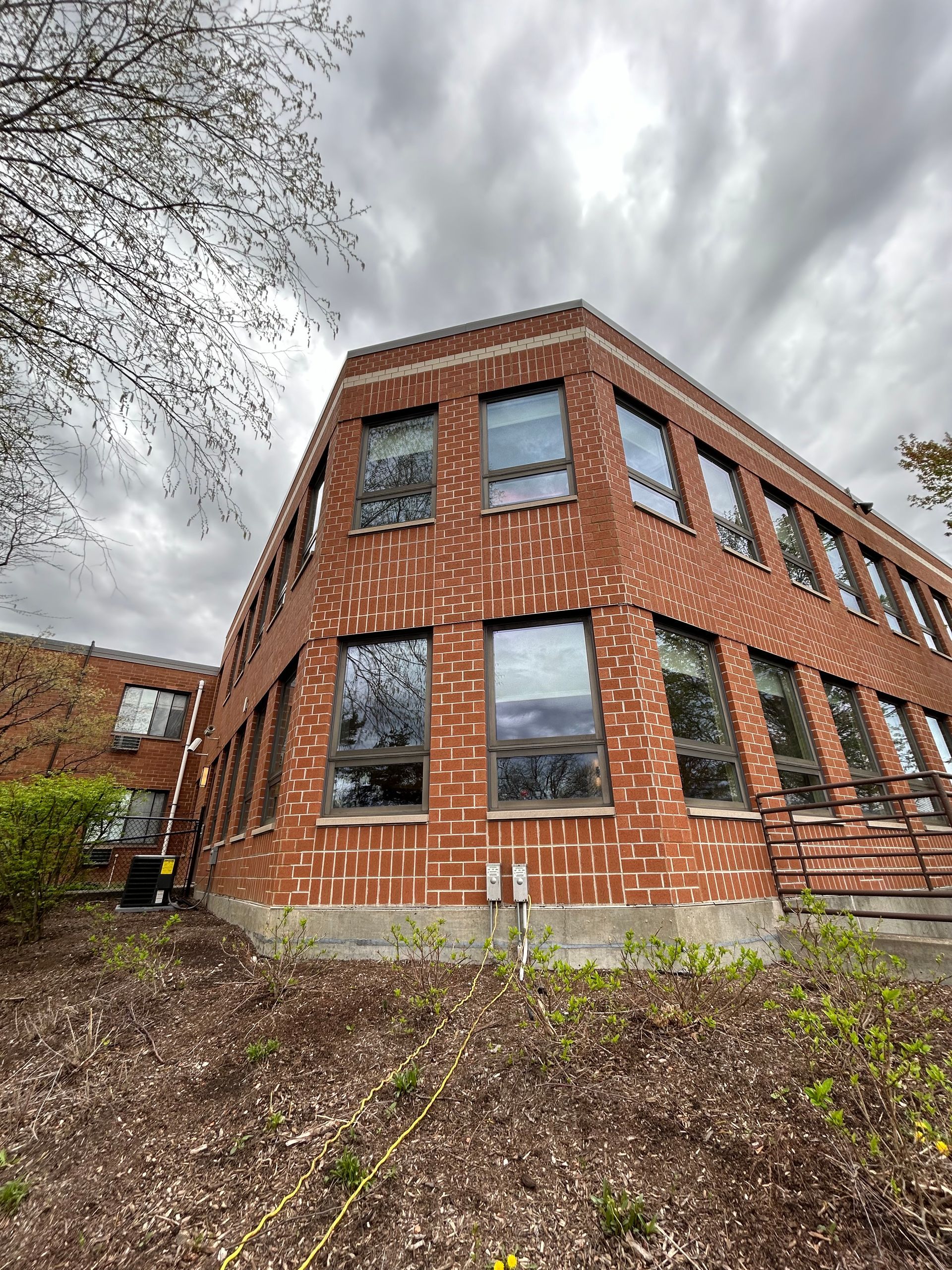 Red brick building with many windows, under a cloudy sky.