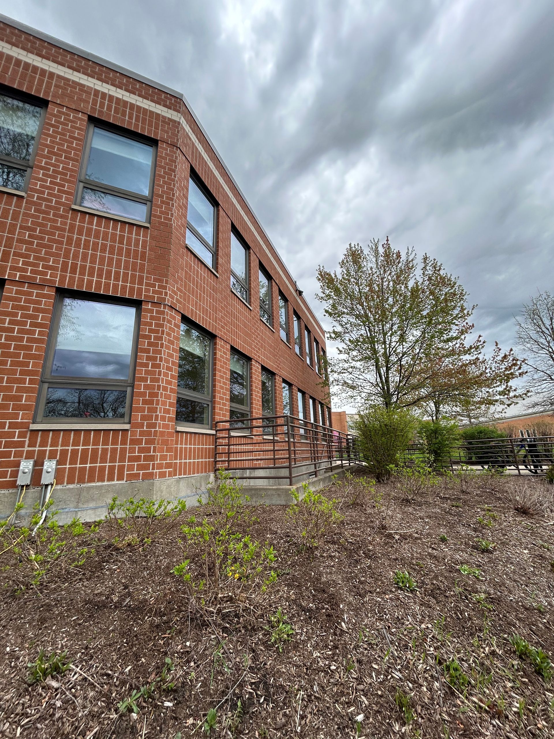 Brick building with windows, ramp access, and overcast sky.