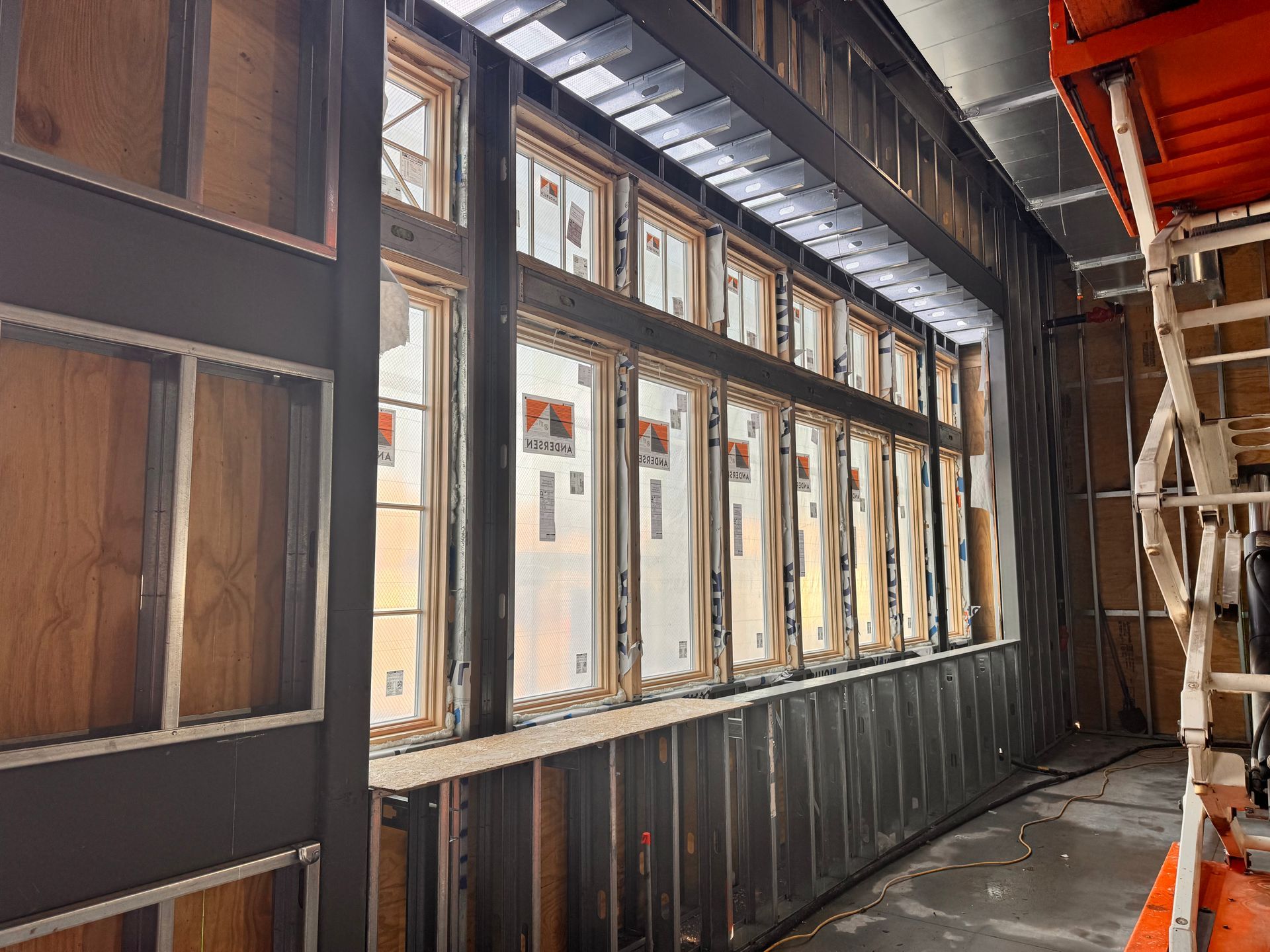 Construction site interior; windows installed in a metal frame, wood studs, and walls.