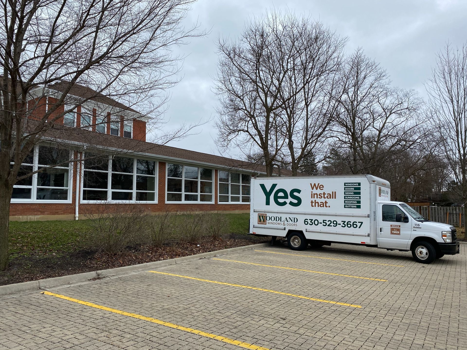 White moving truck parked in front of a brick building, 