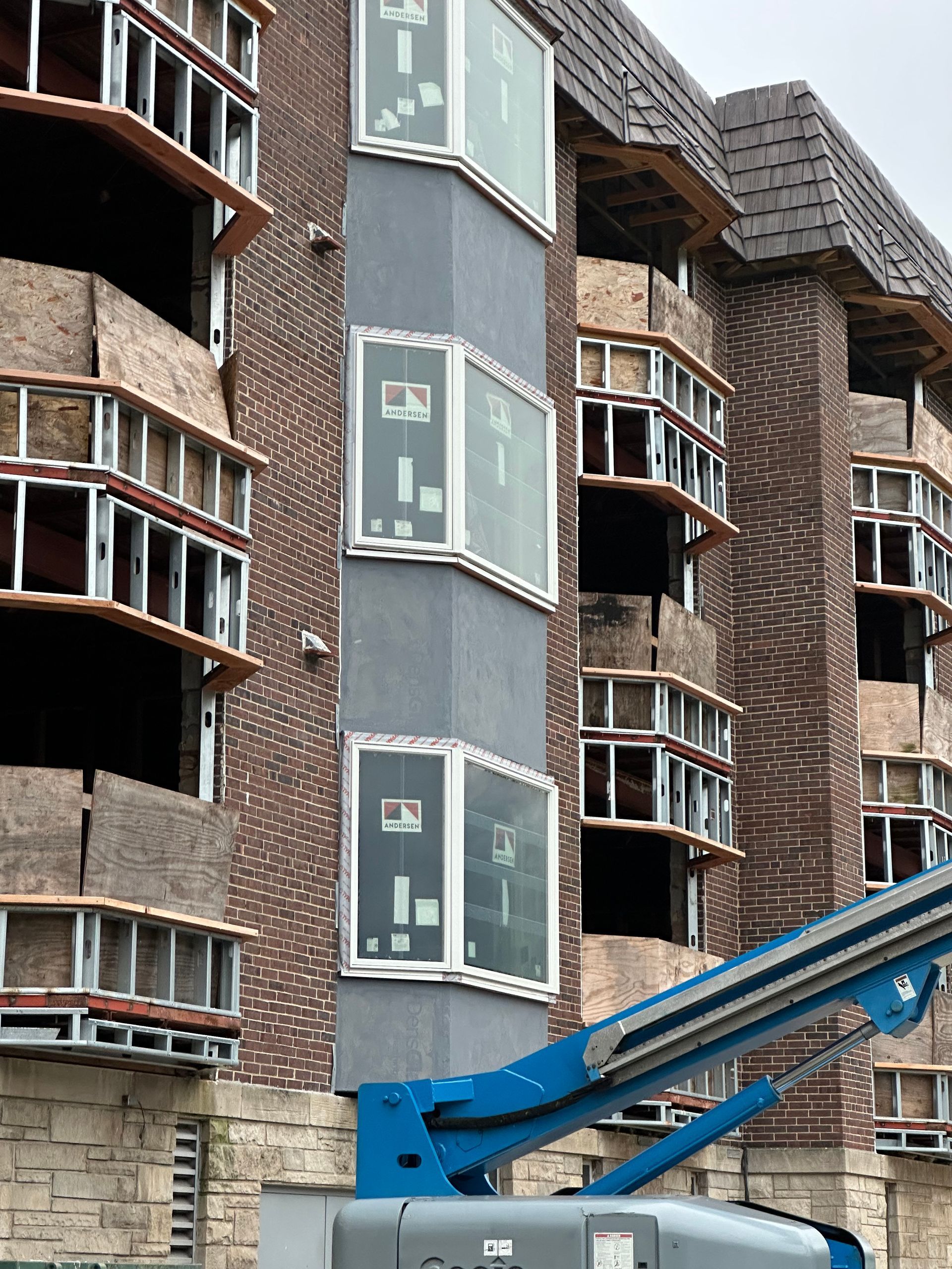Building under construction: brick exterior, scaffolding, new windows, blue lift.