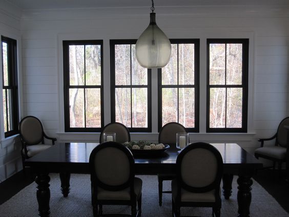 A dining room with a table and chairs and black windows