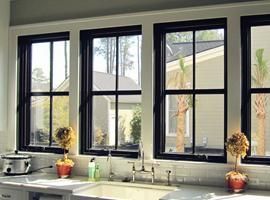 A kitchen with three black windows and a sink.