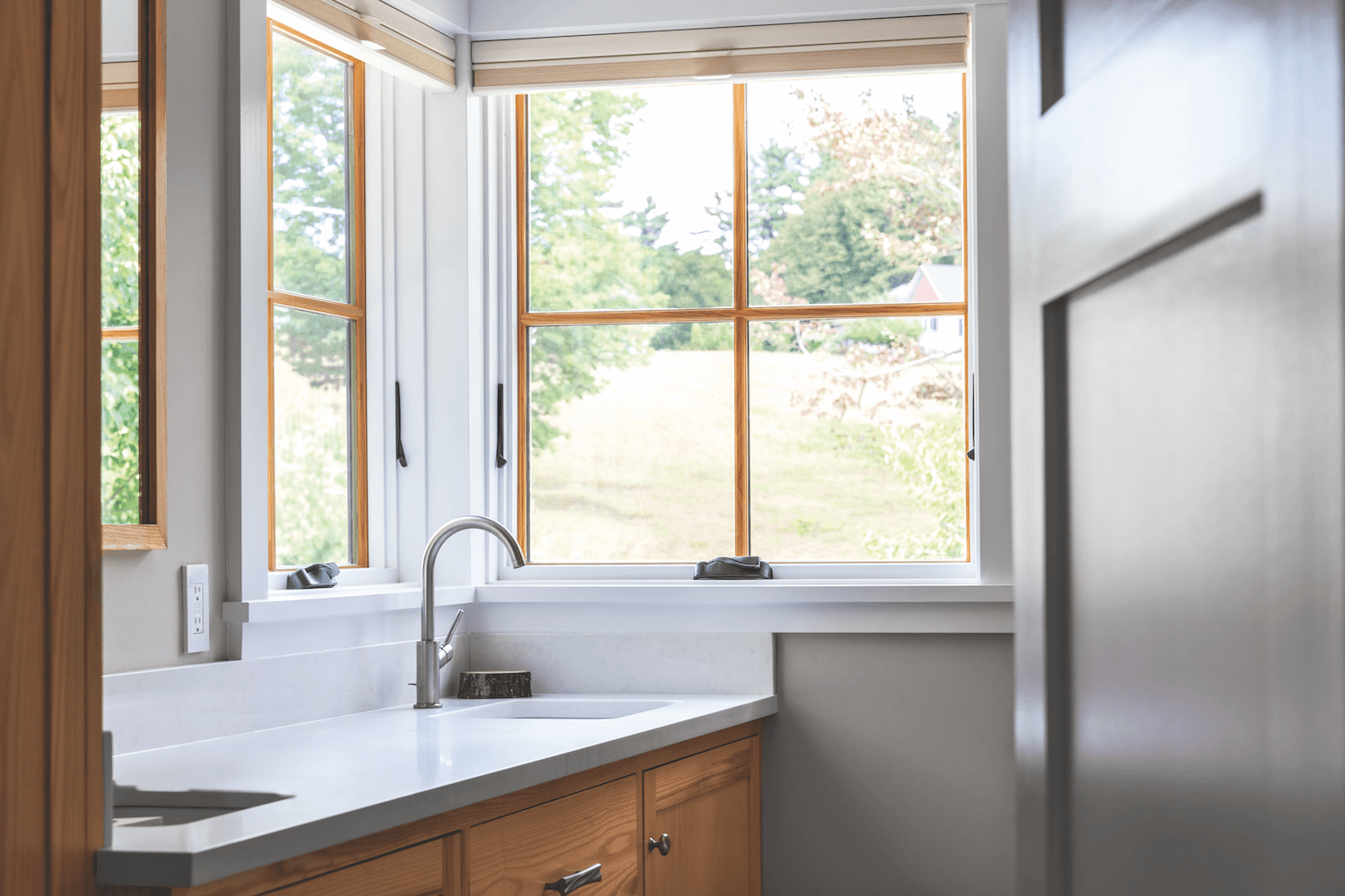 A bathroom with a sink and a window with a view of a field.