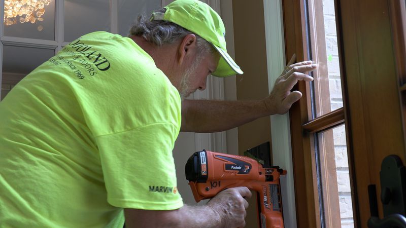 Two men are sitting at a table looking at a laptop computer.