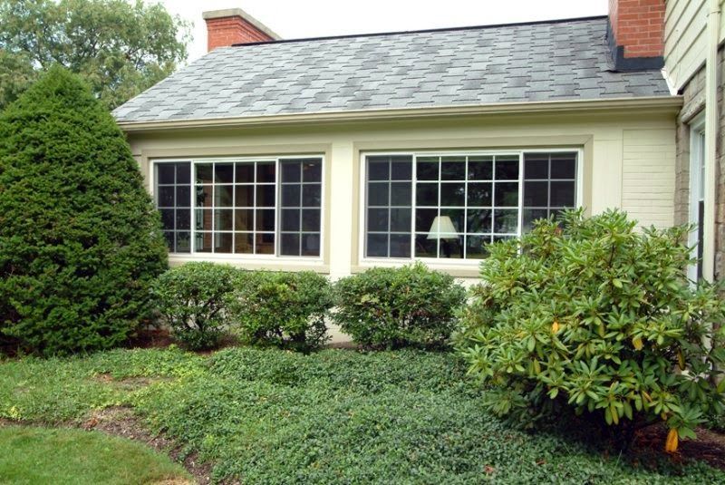 A house with a lot of windows and bushes in front of it.