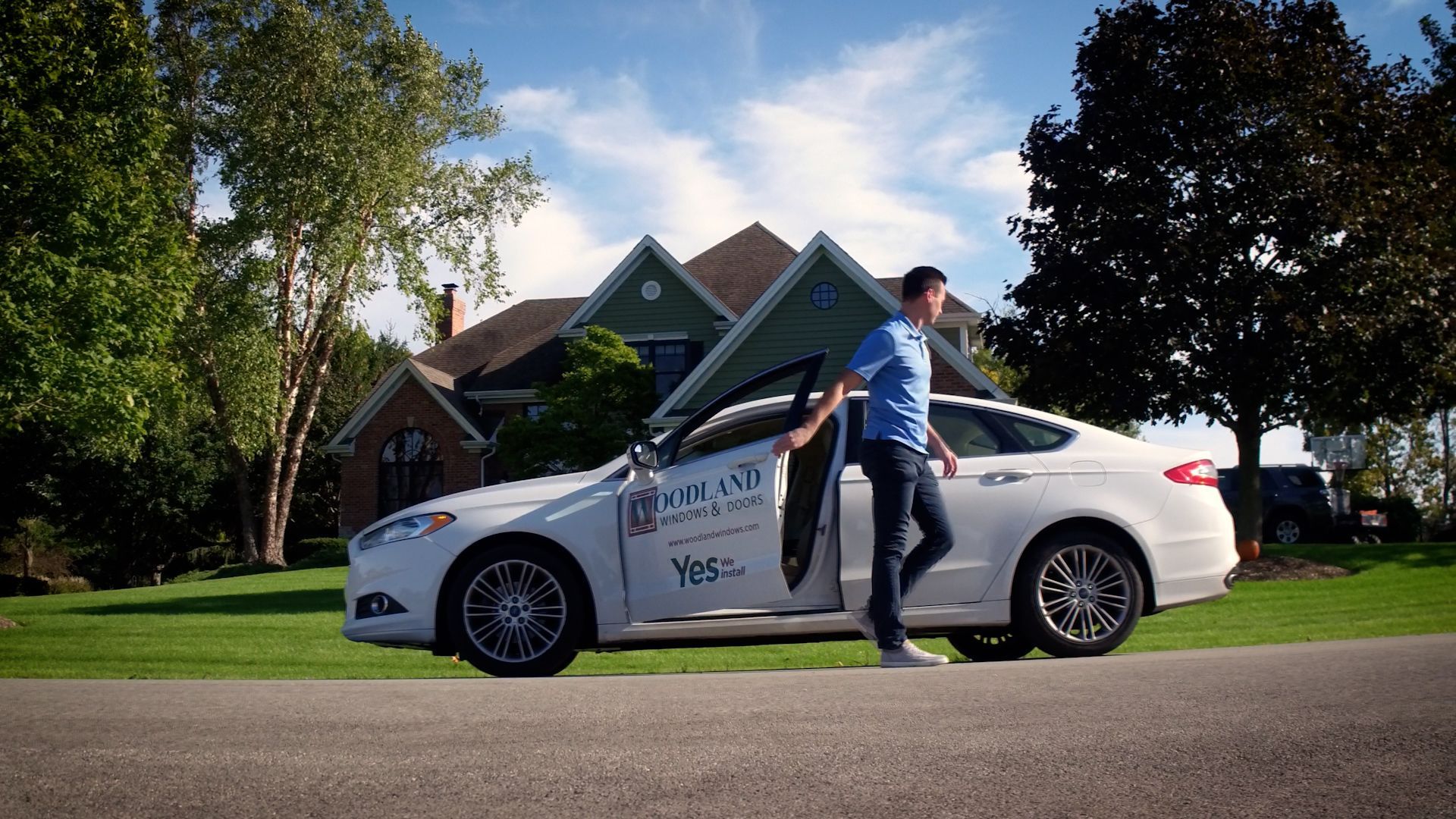 A man is getting out of a white car in front of a house.