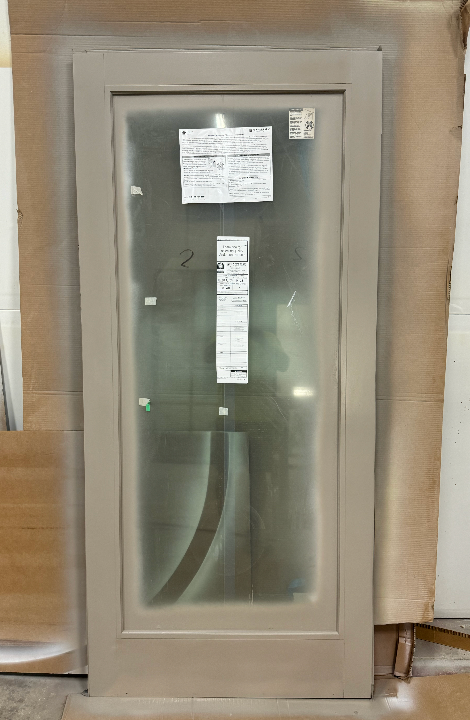 A door with a glass panel is sitting on top of a cardboard box.