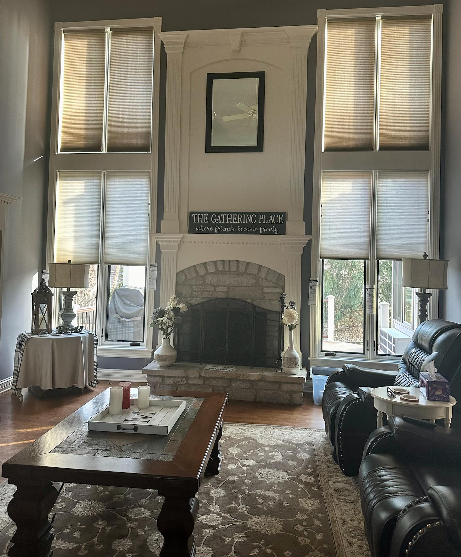 Living room with fireplace, tall windows, and dark leather furniture.