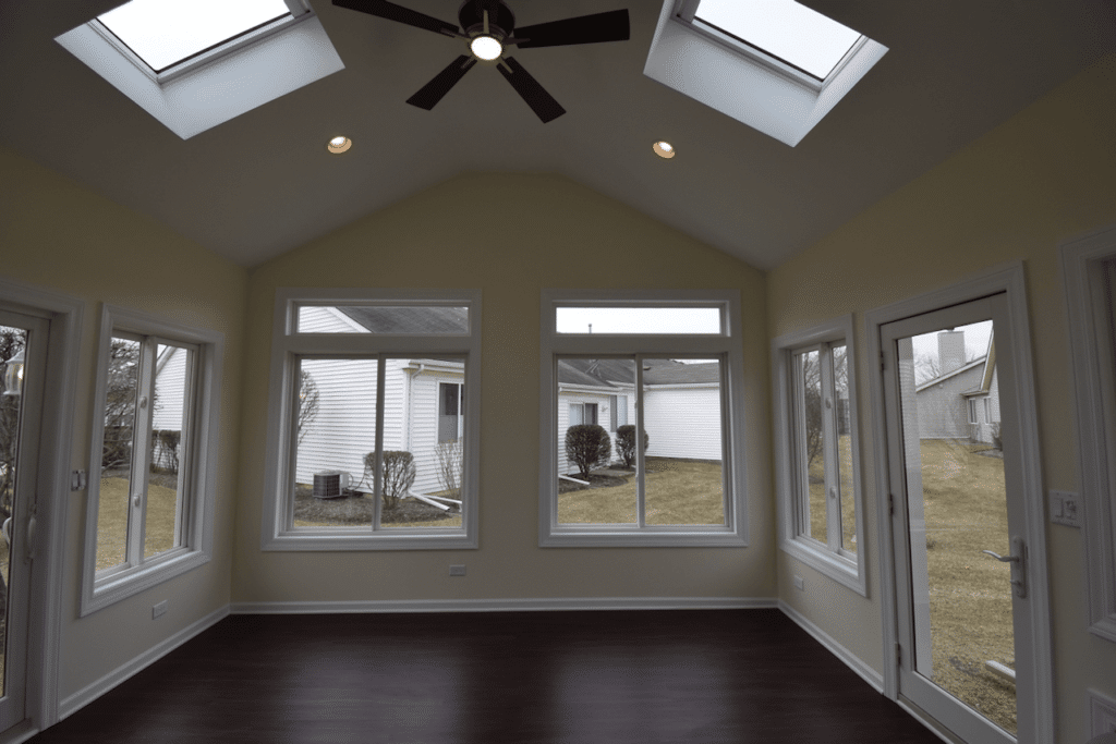 A room with a lot of windows, ceiling fan, and skylights