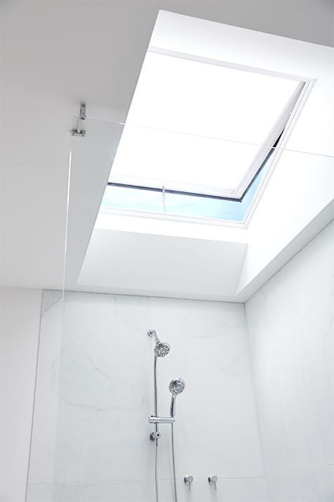 A bathroom with a skylight and a shower head.