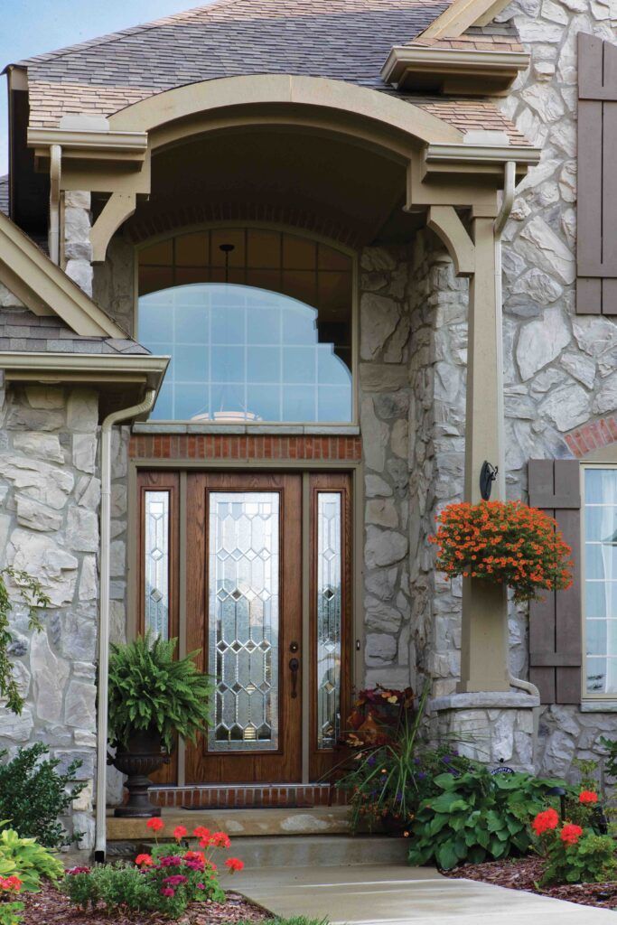 A stone house with a wooden door and flowers in front of it