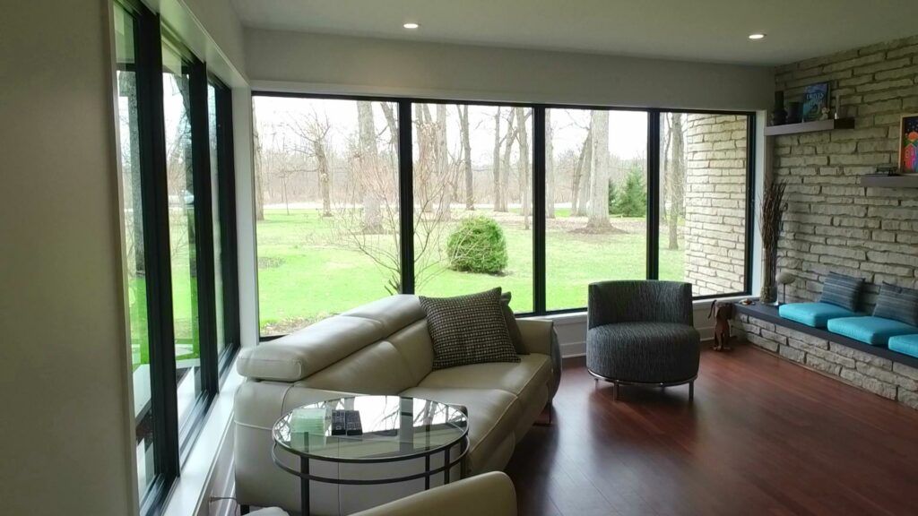 A living room with a couch , chair , table and large windows.