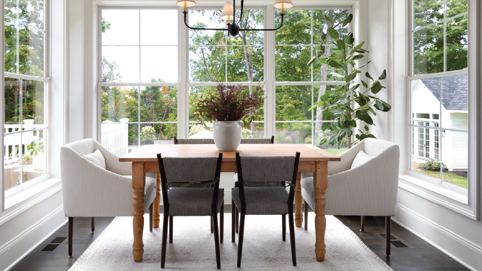 A bedroom with a bed , chair , television and lots of windows.