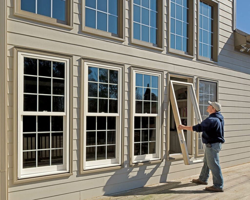 A man is installing a window on the side of a house