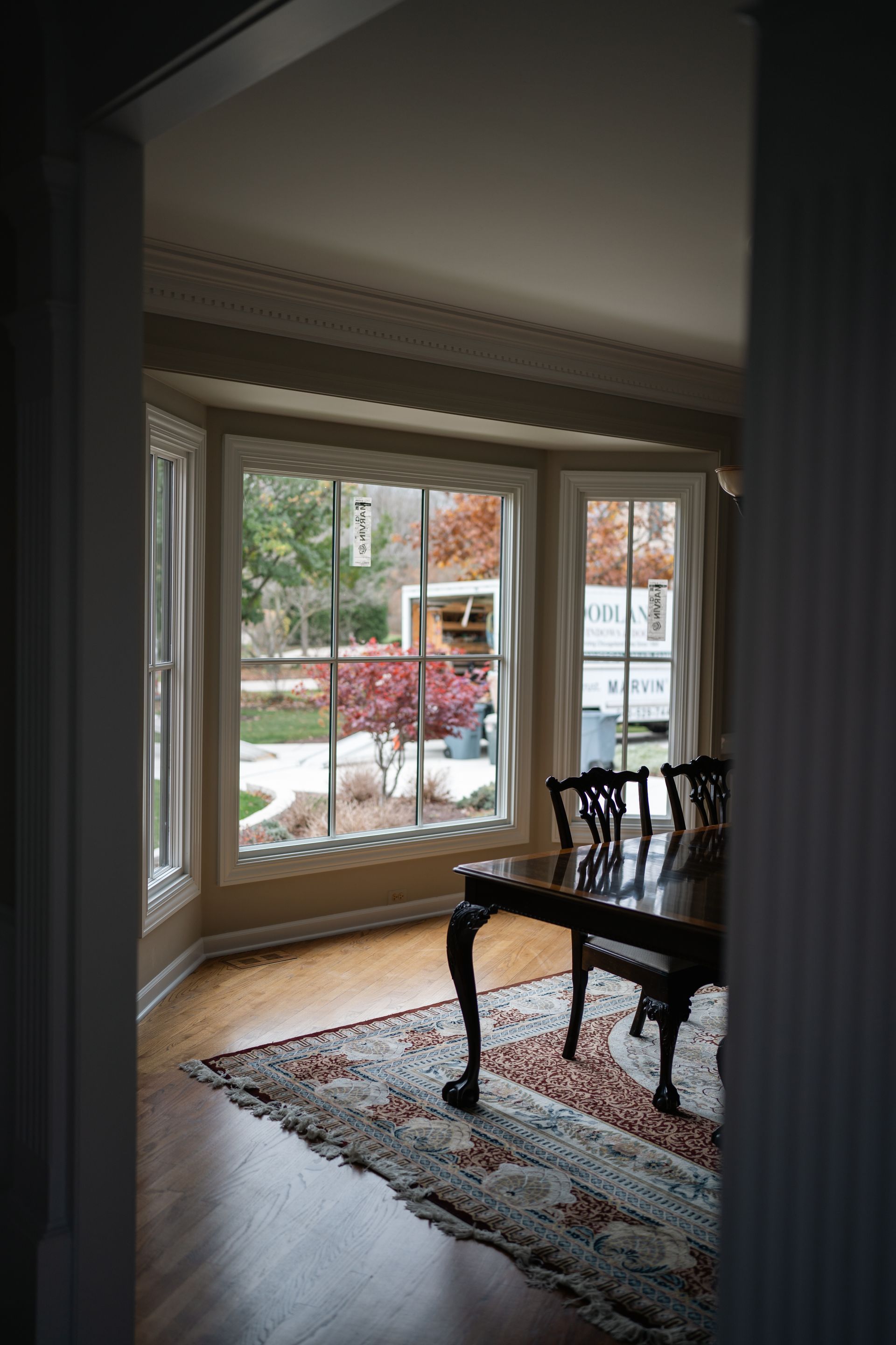 A dining room with a table and chairs in front of a large window, with an outdoor view.