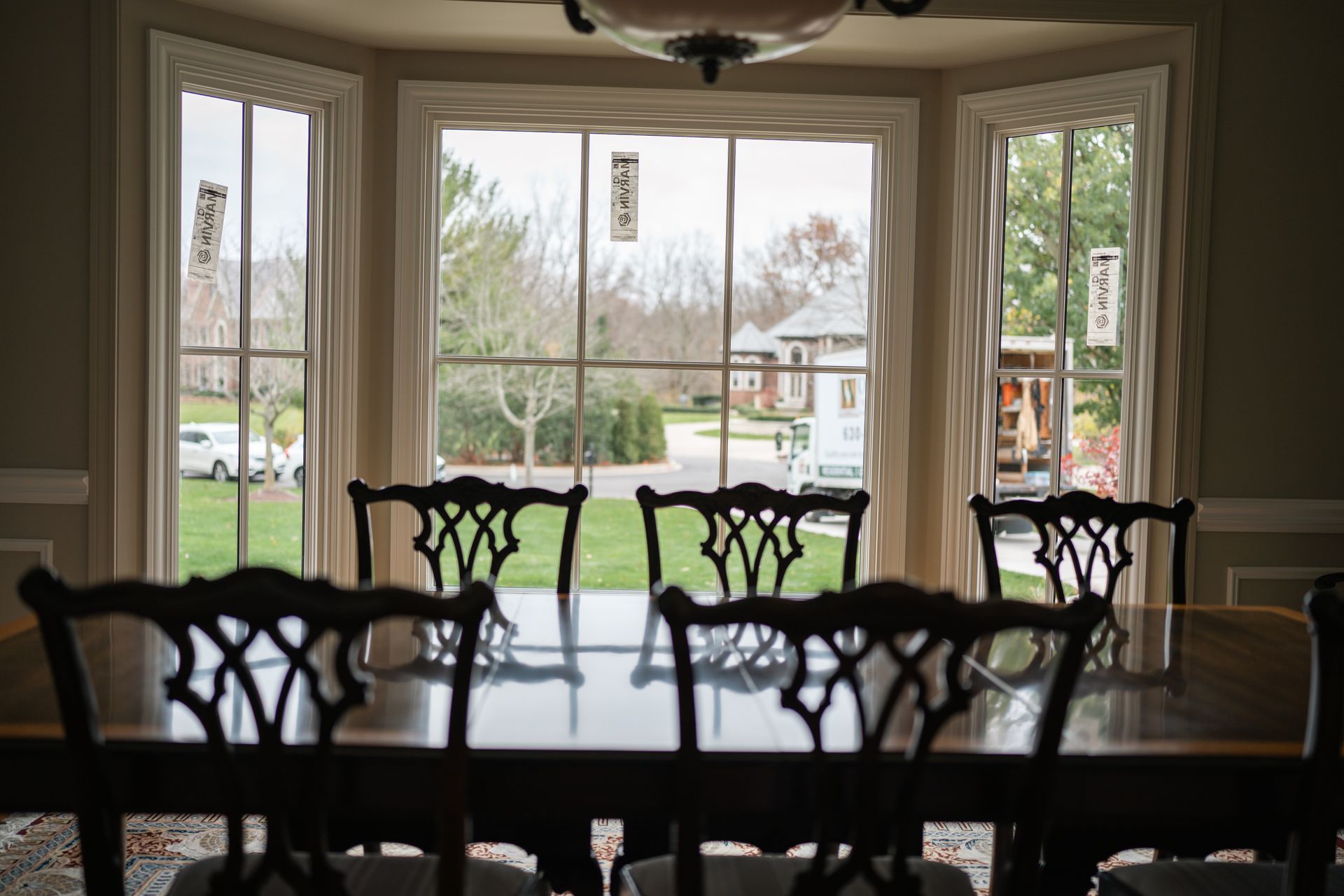 Dining room with a large window overlooking a yard, table and chairs in front.