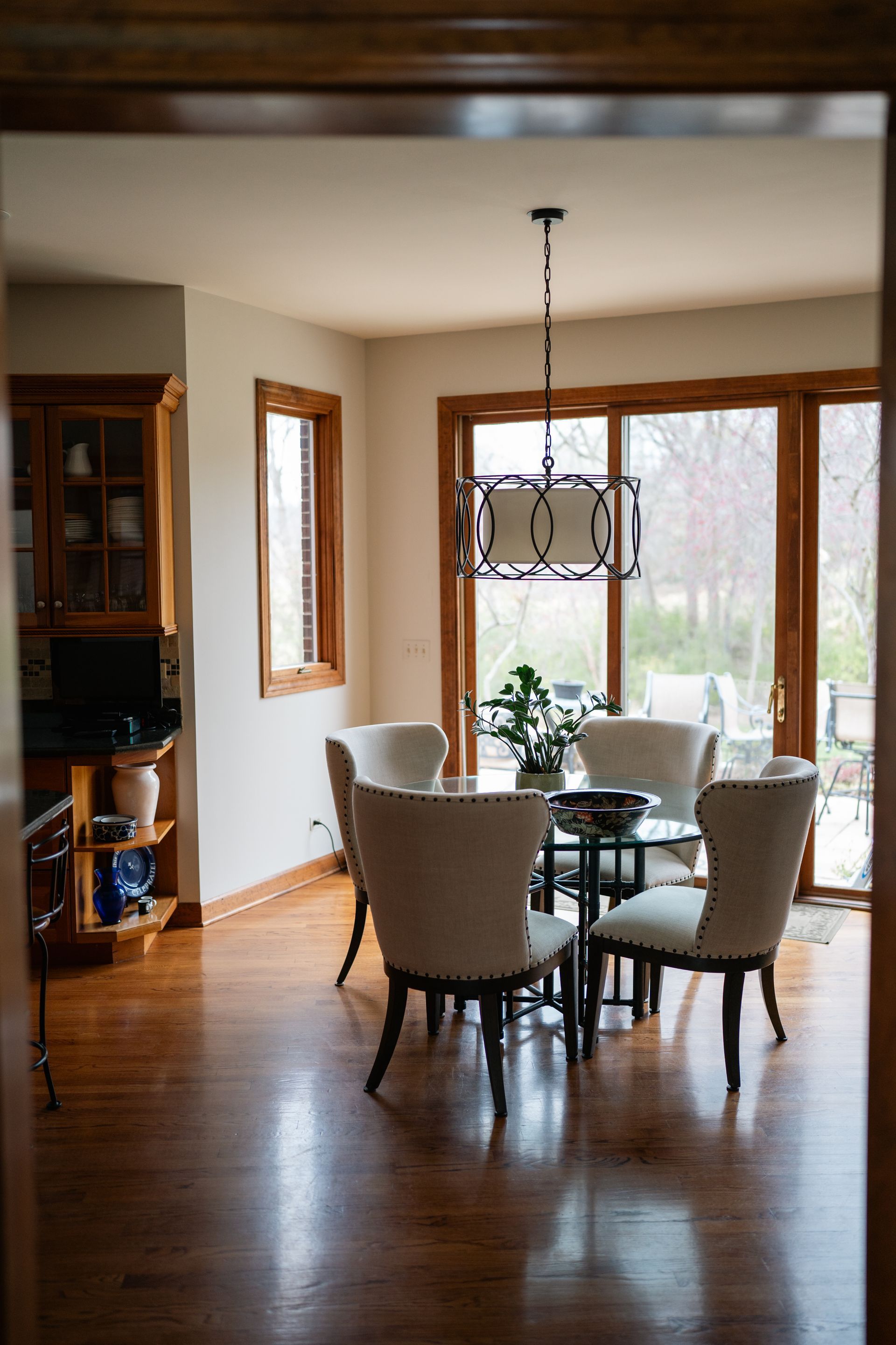 Dining room with a round table, chairs, and a chandelier; natural light from the windows.