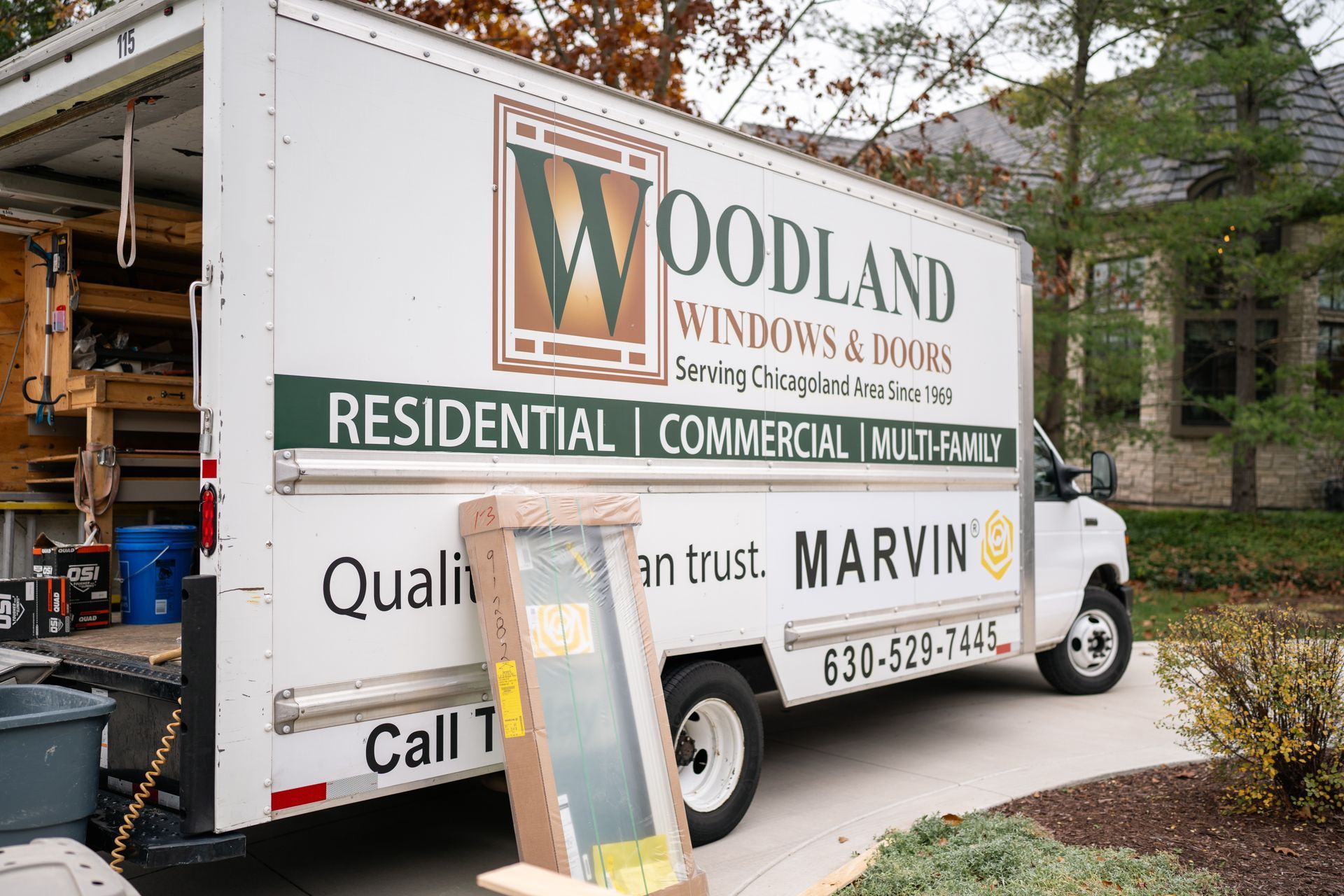 A Woodland Windows & Doors truck parked on a driveway, ready for window installation.