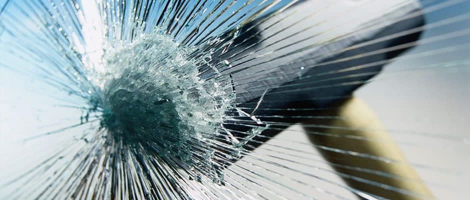 A hammer is hitting a broken glass window.