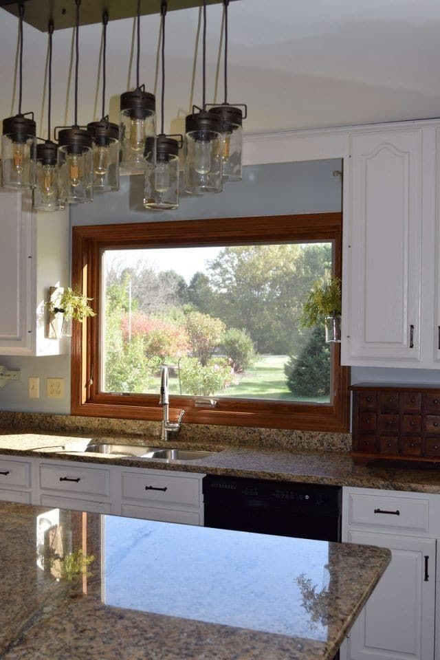 A kitchen with white cabinets and a large window