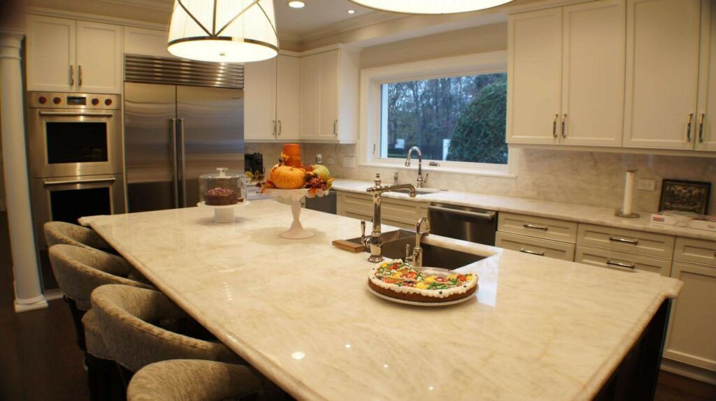 A kitchen with white cabinets and stainless steel appliances and a large island with a cake on it.