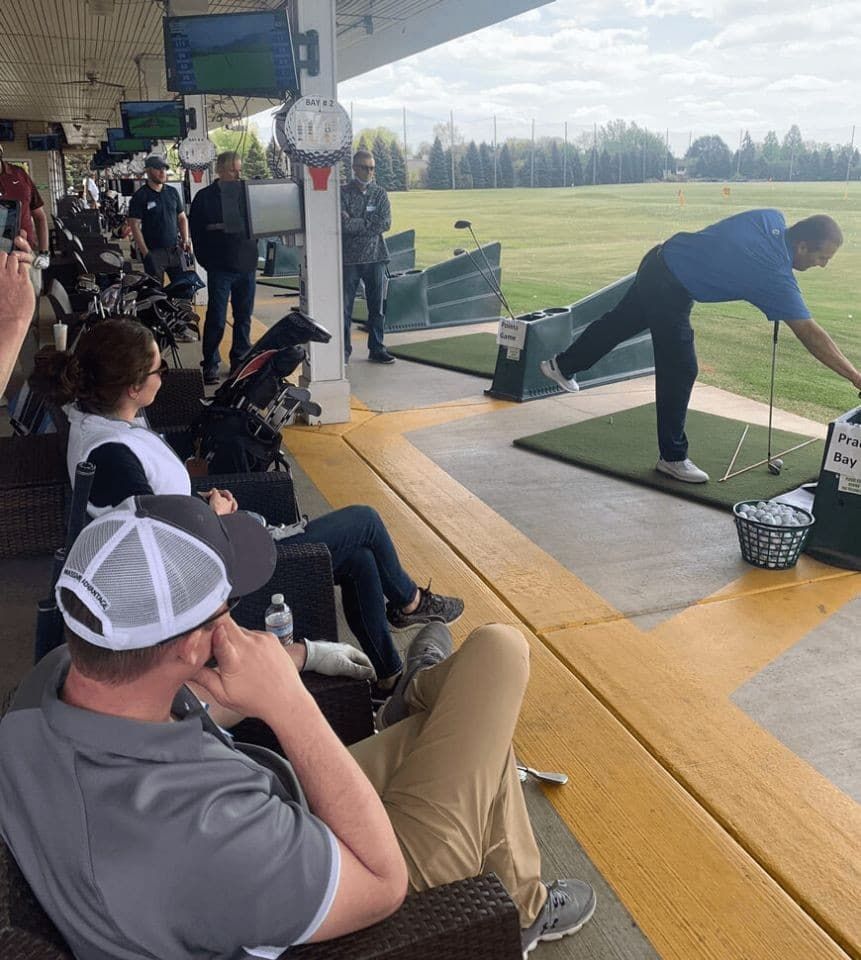 A group of people are watching a man swing a golf club