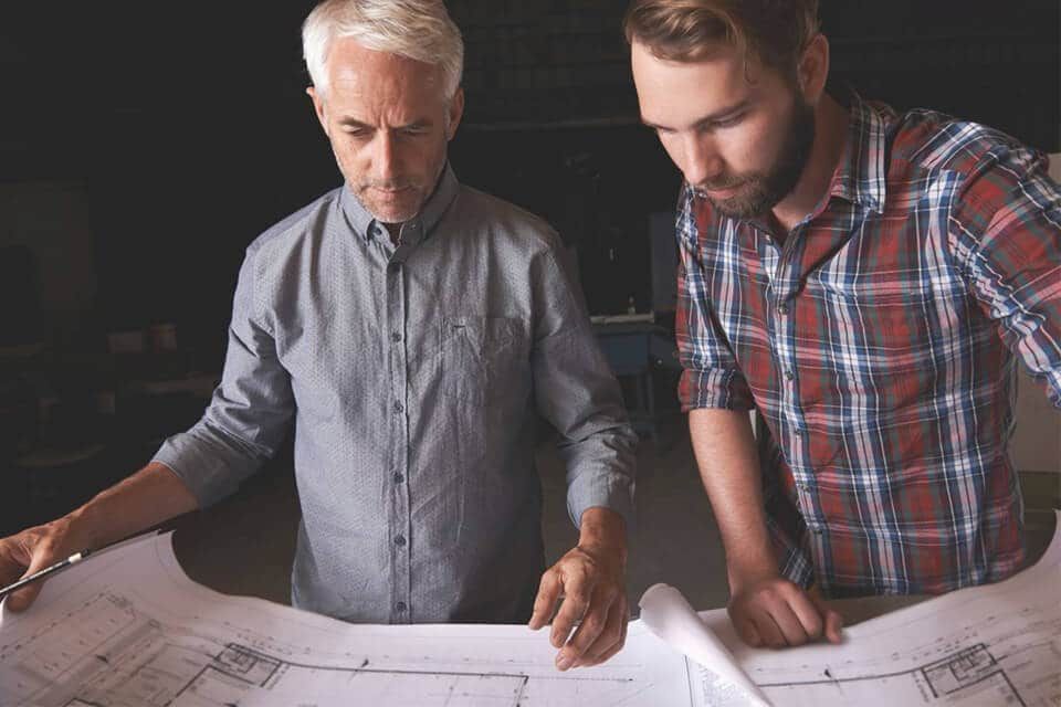 Two men are looking at a blueprint of a house.
