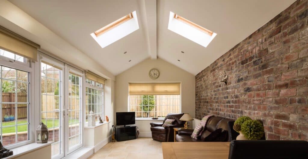 A living room with a brick wall and skylights on the ceiling.