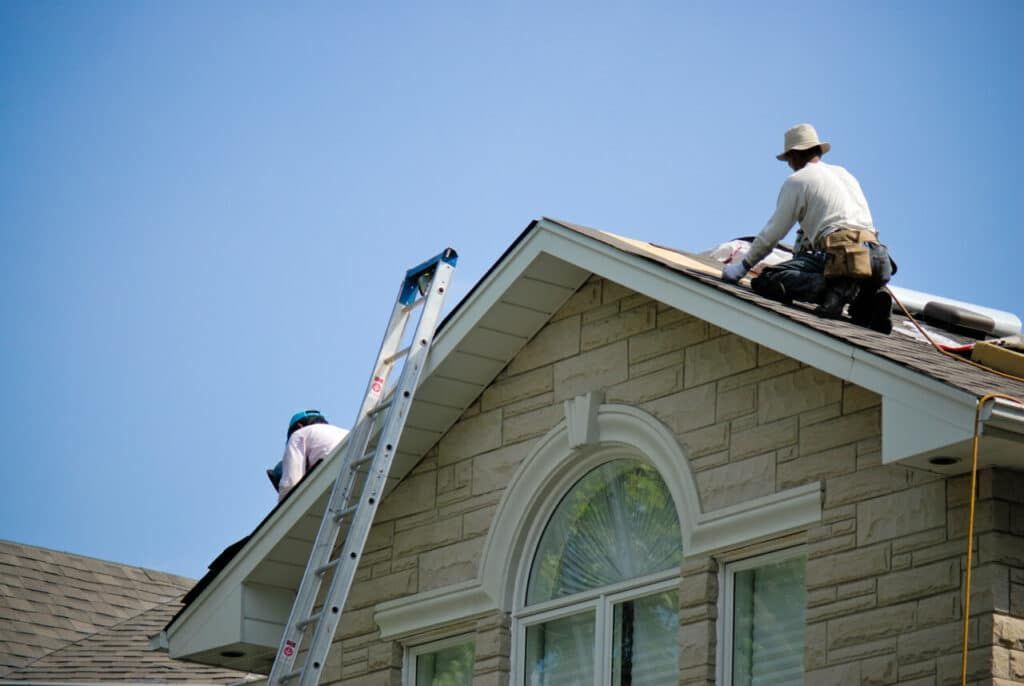 Two men are working on the roof of a house.