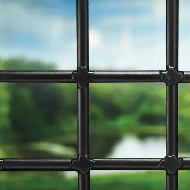 A close up of a black metal fence with a river in the background.