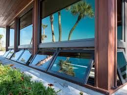 A building with a lot of windows and a reflection of palm trees in the windows.