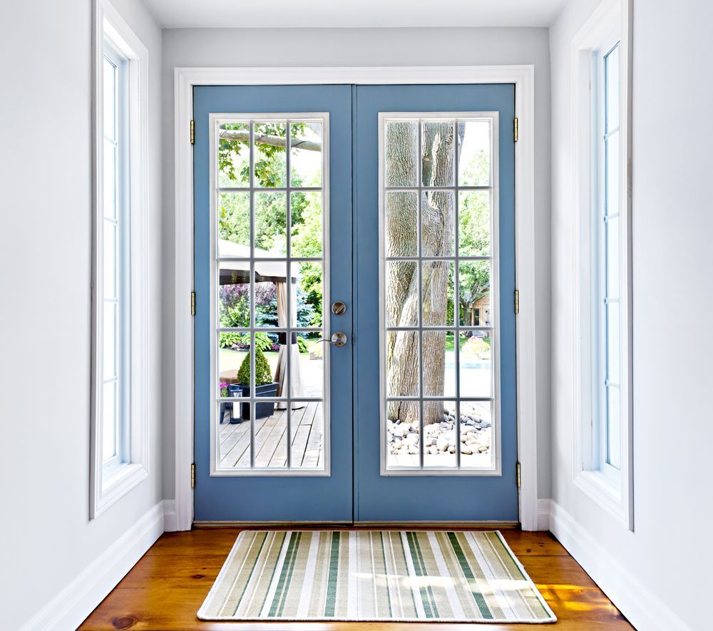 A hallway with blue french doors and a rug on the floor