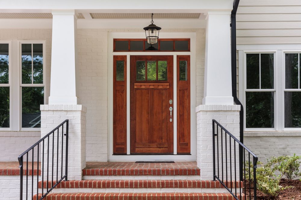 The front door of a white brick house with a wooden door and stairs.