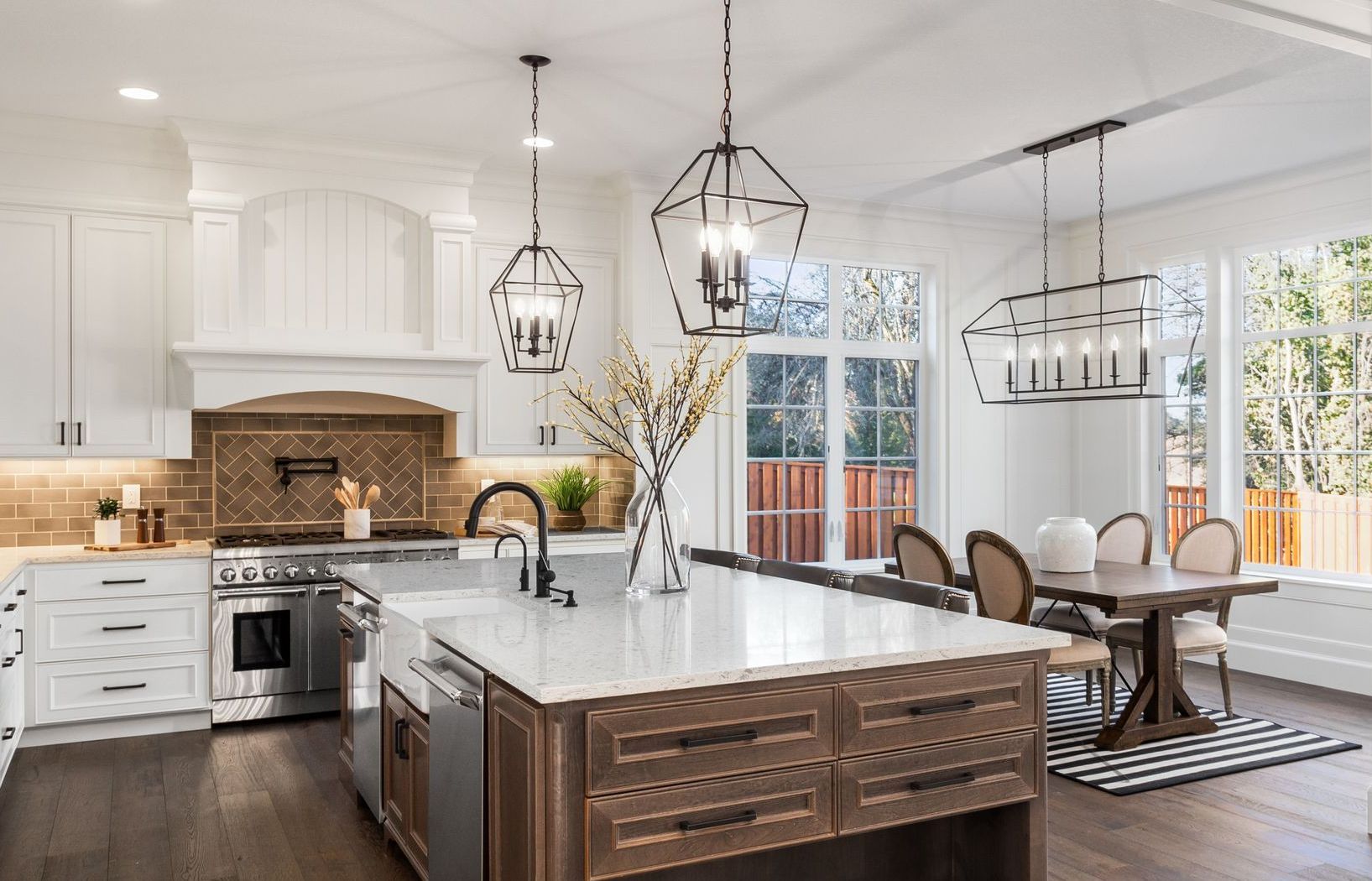 A kitchen with a large island in the middle and a dining room in the background.