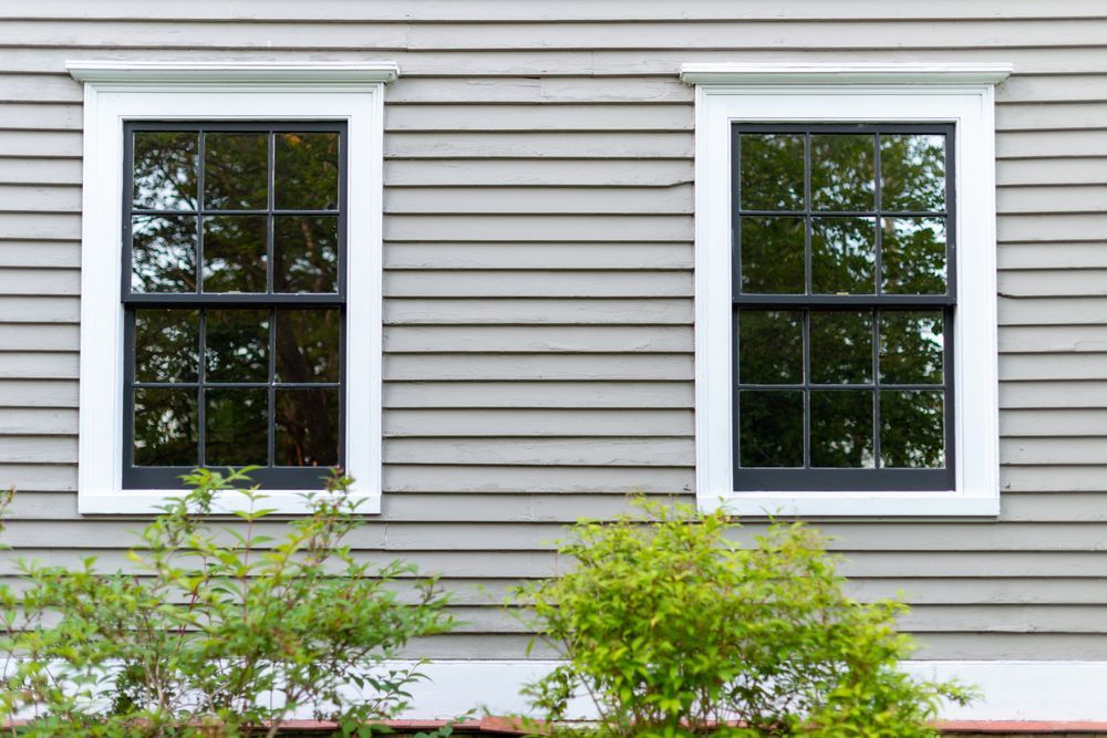 There are two windows on the side of a house.