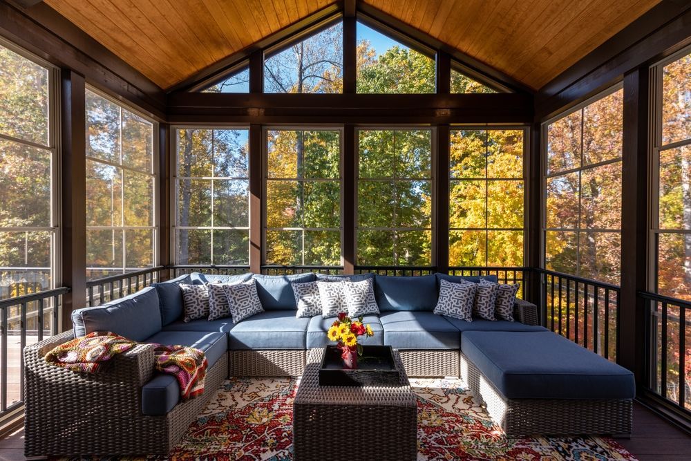 A screened in porch with a couch , chairs , and a table.