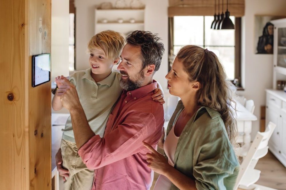 A family is looking at a smart thermostat in their home.