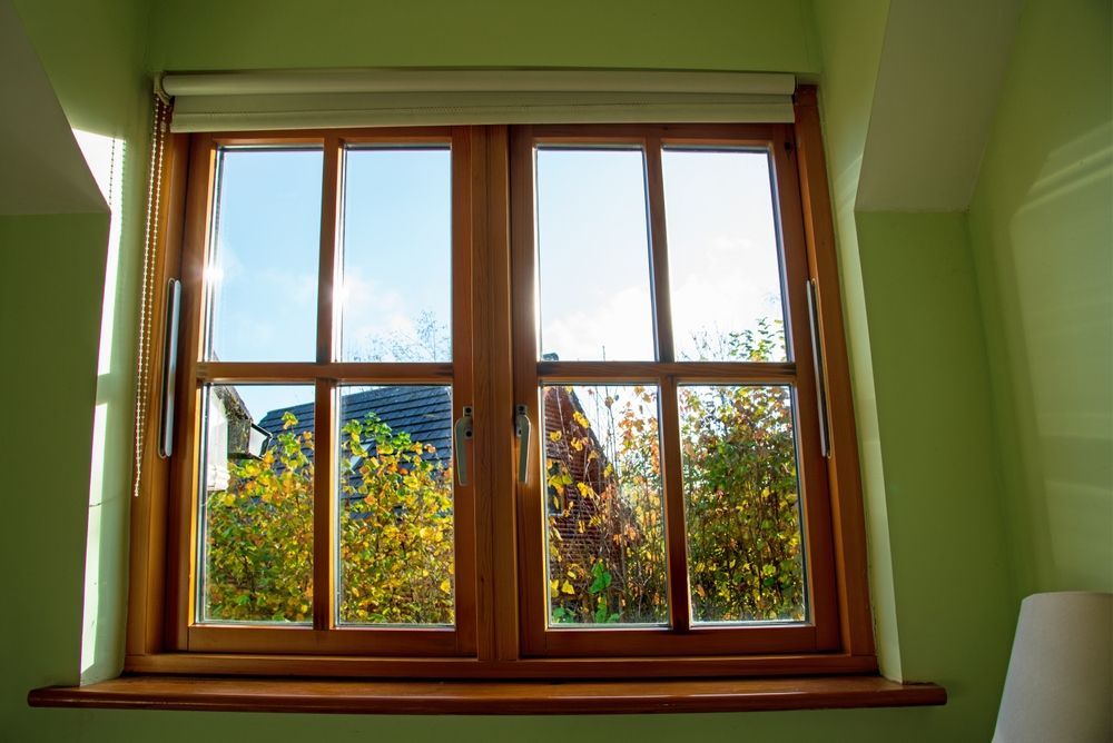 A wooden window with a view of trees and a blue sky