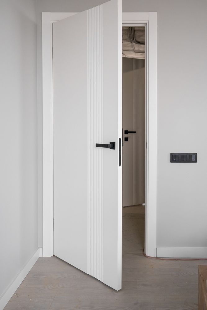 A white door with black handles is open in a room.