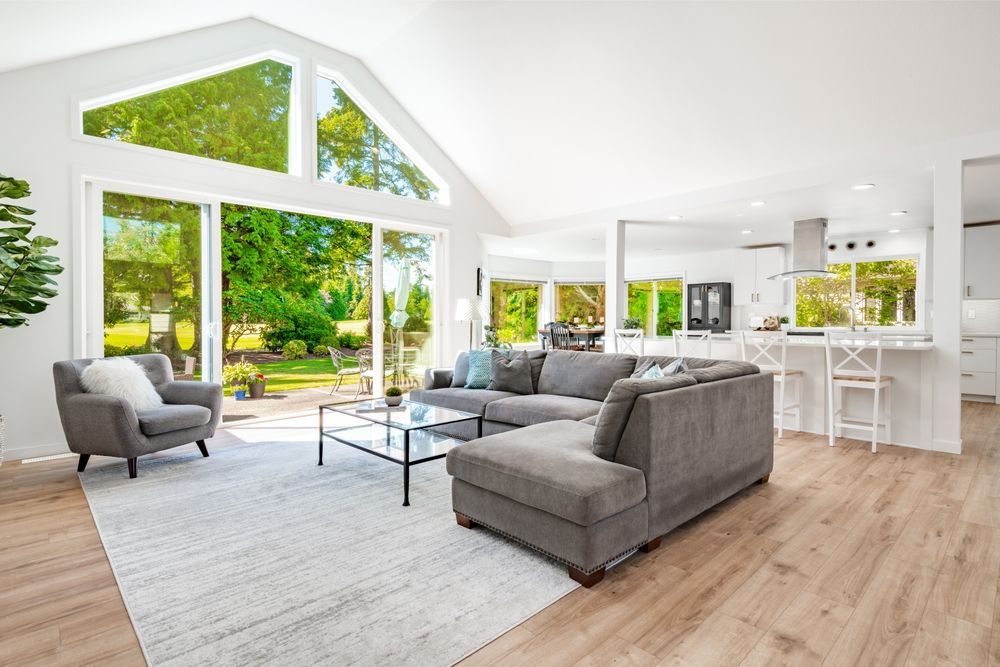 A living room with a couch , chair , coffee table and large windows.