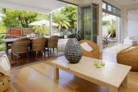 A living room with a coffee table , chairs , and a table with a vase on it.