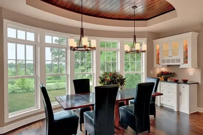 A dining room with a table and chairs and a wooden ceiling.