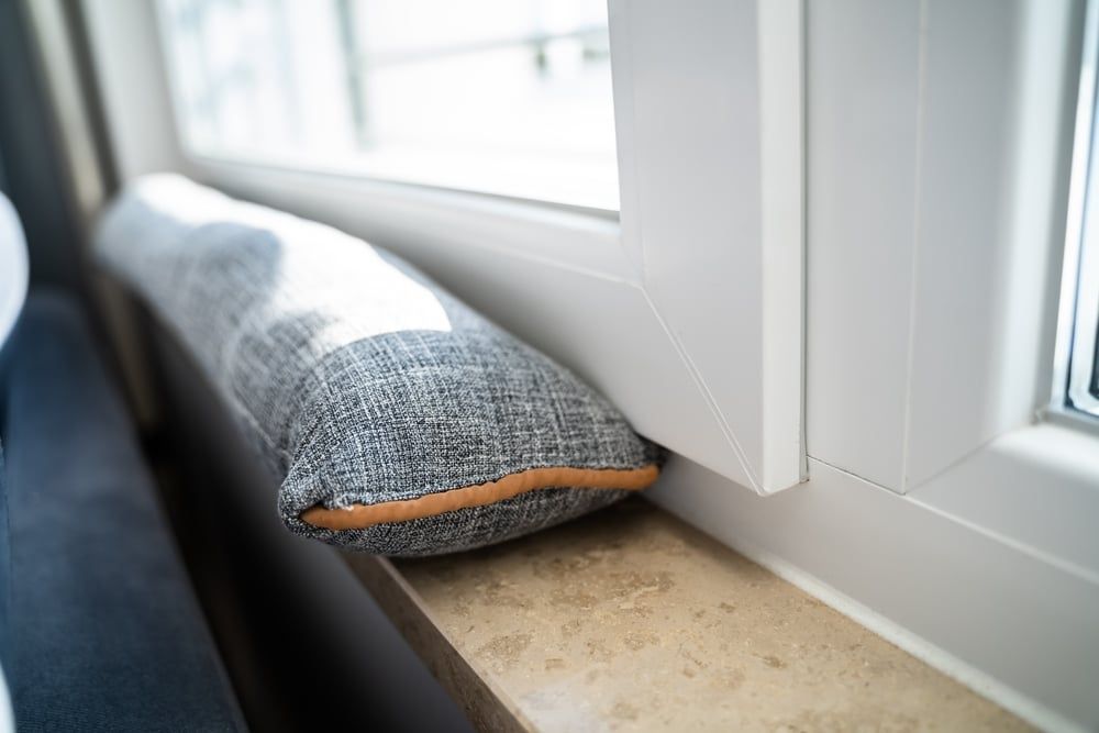 A pillow is sitting on a window sill next to a window.