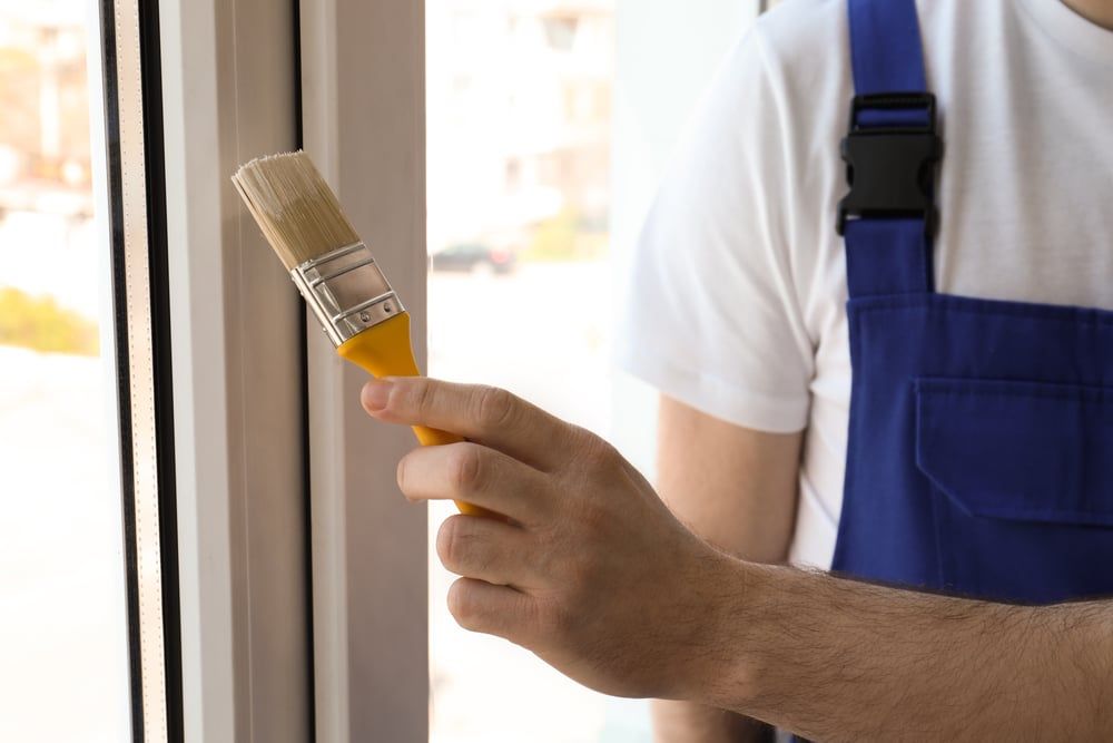 A man is holding a brush in front of a window.