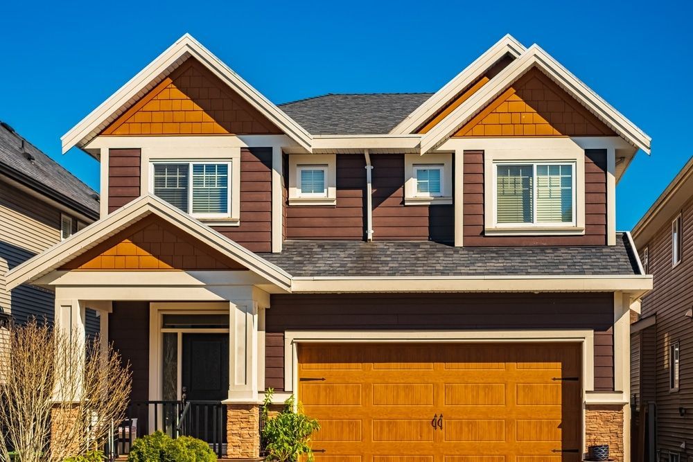 A large house with a large garage door and a blue sky in the background.