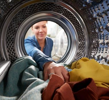 Woman Putting Her Laundry In Washing Machine — Buderim Laundrette in Buderim, QLD
