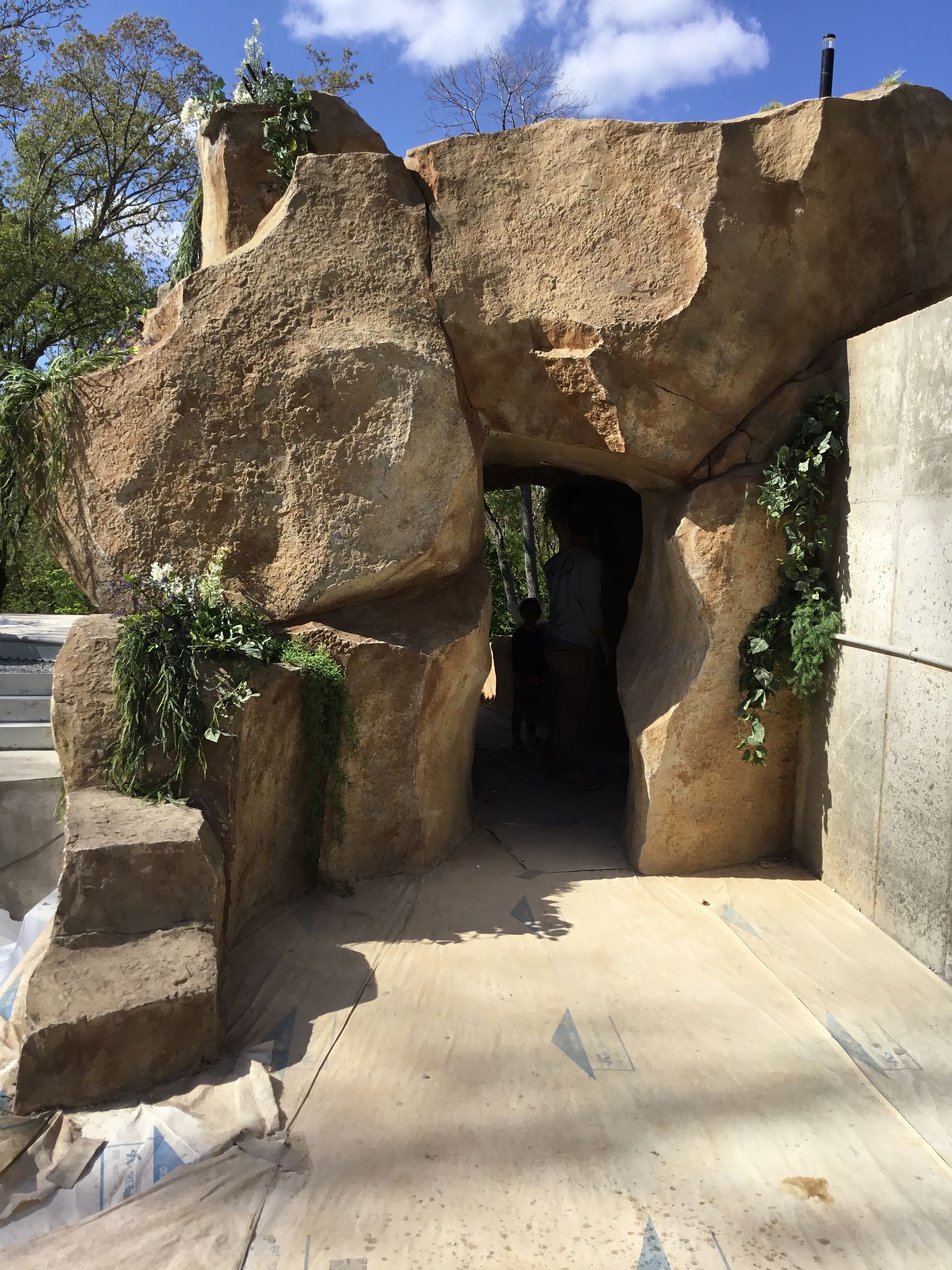 Rock formation archway entrance with a narrow dark passage and stone steps under a blue sky